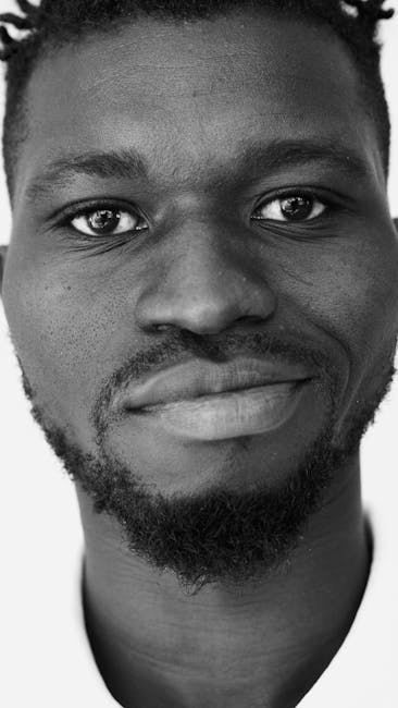 Ritratto in bianco e nero di un uomo sorridente, espressione di autenticità e profondità umana, invito al non giudizio unico.