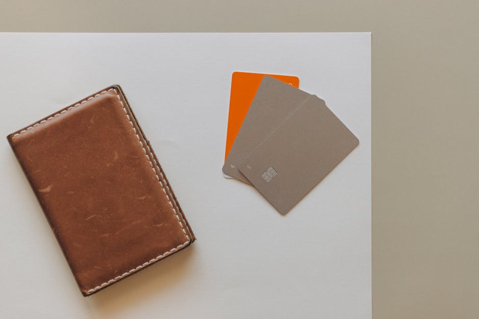 Portafoglio in pelle marrone e carte di credito colorate su sfondo bianco, strumenti per una gestione efficace del portafoglio finanziario.