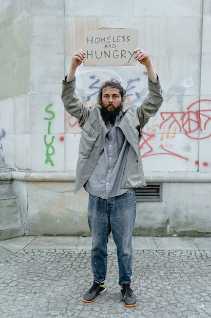Uomo senzatetto con cartello Homeless and Hungry, metafora precarietà lavoro docenti sostegno e necessità riforma corsi specializzazione.