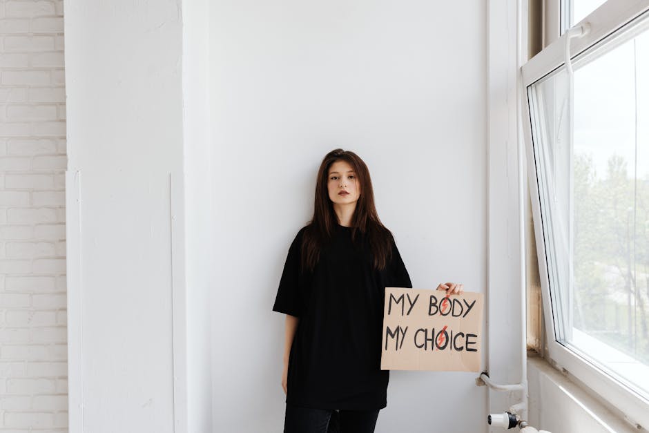 Giovane donna con cartello 'My Body My Choice' in difesa delle preferenze GPS 2026 e della libertà di scelta della sede di lavoro.