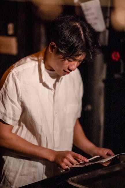 Studente concentrato esamina materiale didattico, esempio di apprendimento attivo e tecniche avanzate nell'insegnamento creativo.