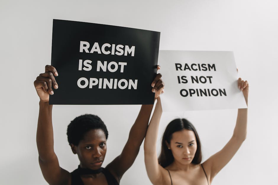 Due donne manifestano contro il razzismo con cartelli con la scritta 'Il razzismo non è un'opinione' in un contesto di lotta all'apartheid.