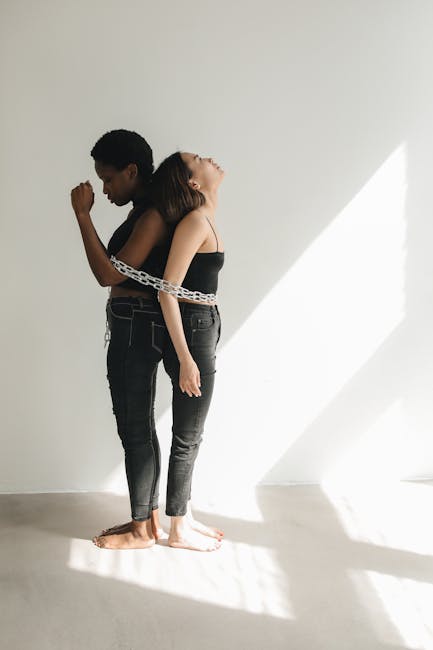 Atena e Minerva: due donne legate da una catena, simbolo di dualità e forza interiore nell'articolo sulle dee greche e romane.