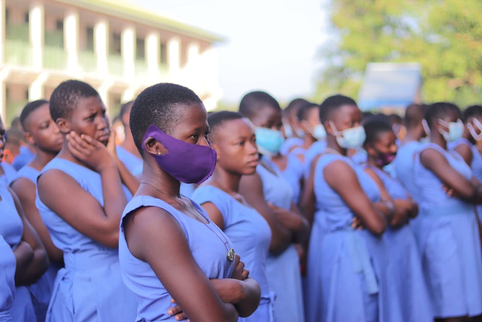 Studentesse africane con mascherine in uniforme scolastica blu, misure di sicurezza Covid-19, prevenzione del contagio in ambito scolastico.