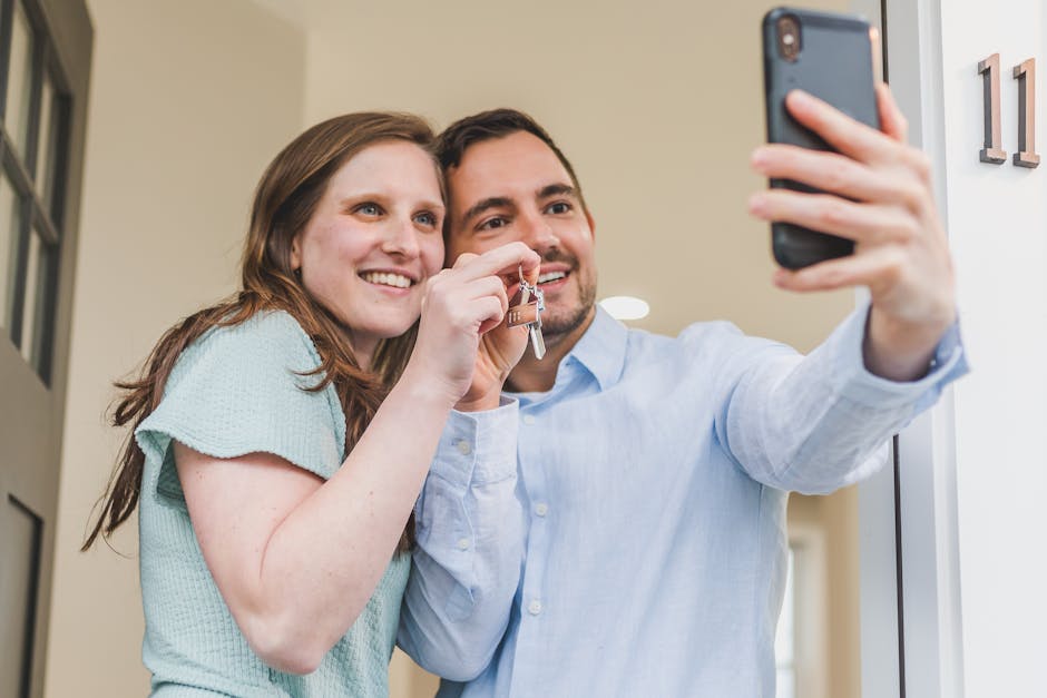 Giovane coppia felice si fa un selfie con le chiavi di casa nuova, simbolo di futuro e competenze per costruire insieme.