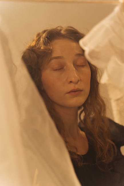 Ritratto di donna con occhi chiusi immersa in un'atmosfera bucolica e sensoriale, espressione di pace e bellezza naturale.