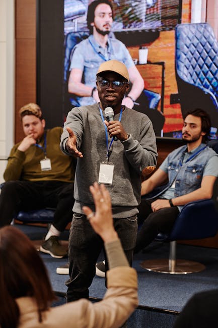 Studente che parla al microfono durante un dibattito in classe, promuovendo il dialogo e la crescita cognitiva tra i partecipanti.