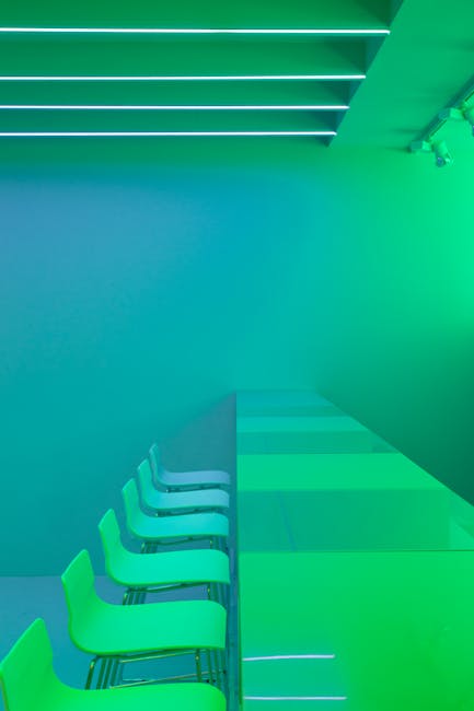 Tavolo e sedie regolabili in ambiente moderno con illuminazione verde e blu per articolo sui vantaggi innovativi.