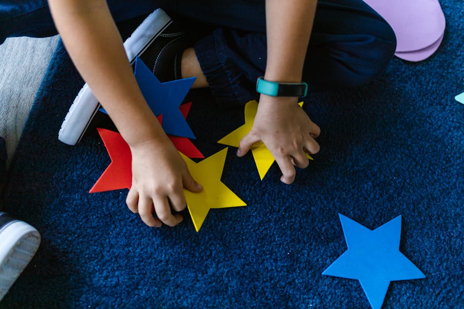 Bambino gioca con stelle colorate di cartone, attività creativa per imparare l'inglese con Trinity Stars, sviluppo linguistico e manuale.