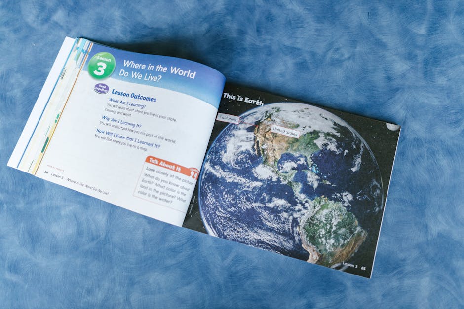 Libro di testo scolastico aperto con mappa del mondo, utile per illustrare la formazione ATA e le posizioni economiche durante le ferie.
