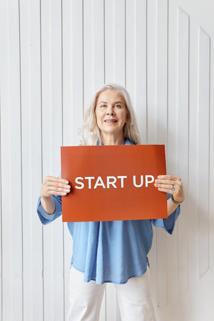 Insegnante ATA mostra cartello START UP: opportunità di crescita professionale nel rinnovo del CCNL scuola e personale ATA