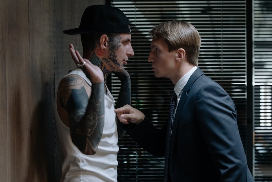 Uomo in giacca e cravatta che rimprovera un uomo tatuato: implicazioni etiche dell'IA e sessualizzazione delle immagini di Grok.