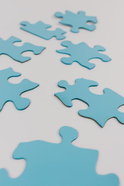 Pezzi di puzzle azzurri sparsi su sfondo bianco, metafora della sinergia MIUR USR per l'istruzione di qualità in Italia
