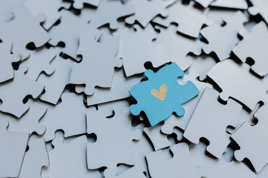 Un pezzo di puzzle blu con un cuore si distingue tra i pezzi grigi, simbolo dell'autismo ad alto funzionamento e della sua unicità.