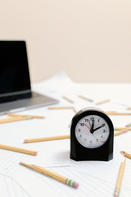 Orologio, laptop e matite spezzate su foglio a righe: metafora del burnout e della pressione lavorativa per i docenti.
