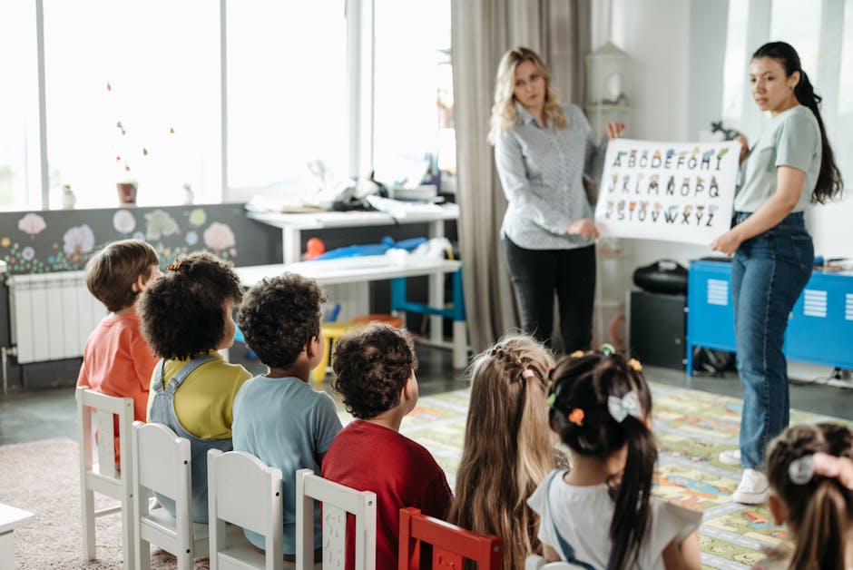 Bambini seduti ad ascoltare le maestre: registro elettronico per nidi e infanzia, nuove modalità di comunicazione scuola-famiglia.