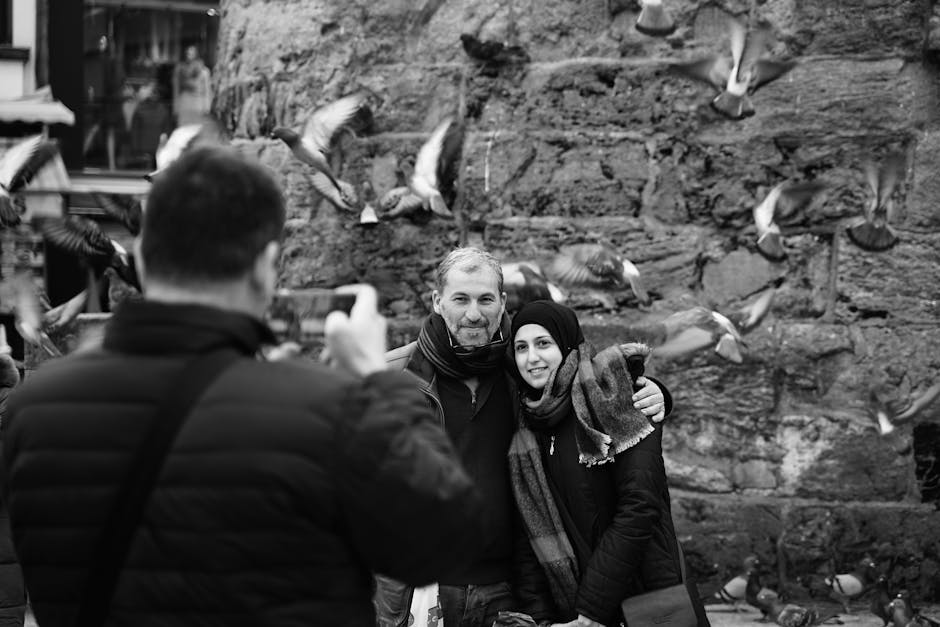 Coppia sorridente fotografata tra i piccioni, espressione di unicità e autenticità in un contesto urbano dinamico.