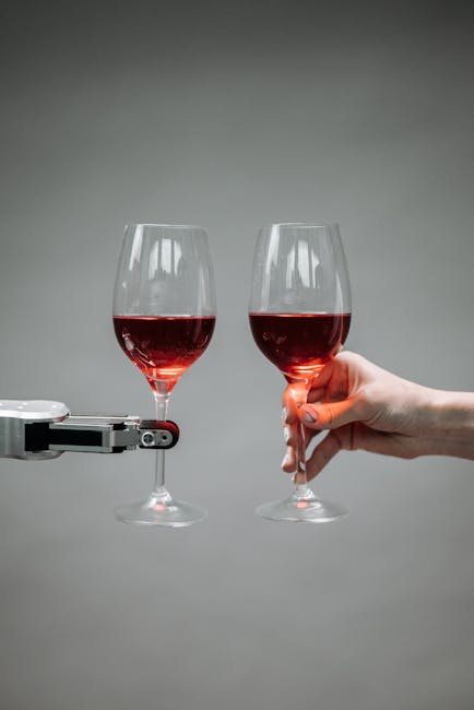 Due calici di vino rosso: uno tenuto da mano umana, l'altro da braccio robotico. Integrazione uomo-macchina nel sistema unico.