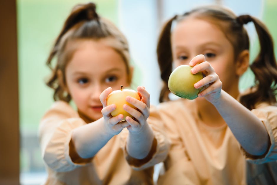 Due bambine mostrano mele colorate: un'immagine per l'educazione alimentare e l'importanza della frutta per la salute dei bambini.