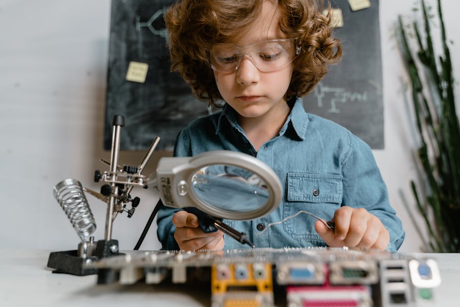Bambino con occhiali protettivi che salda componenti elettronici, un approccio innovativo per l'apprendimento STEM e lo sviluppo di competenze matematiche.