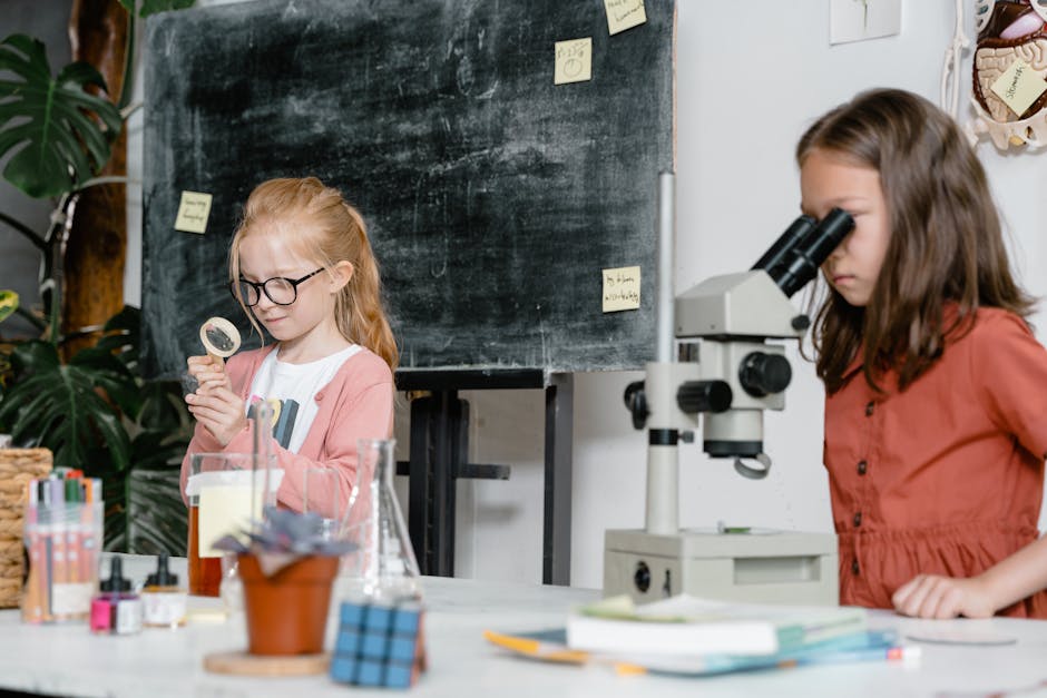 Bambine esplorano le proprie emozioni attraverso la scienza a scuola con lente d'ingrandimento e microscopio