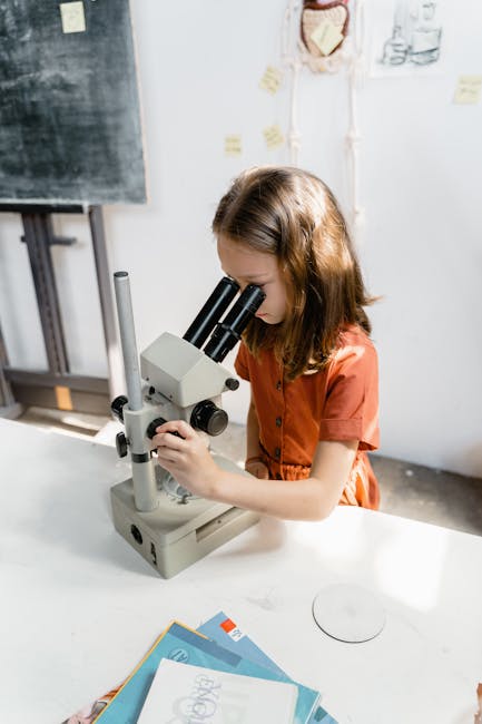 Ragazza che usa un microscopio in laboratorio per lo studio della fisica, apprendimento coinvolgente e strategie efficaci