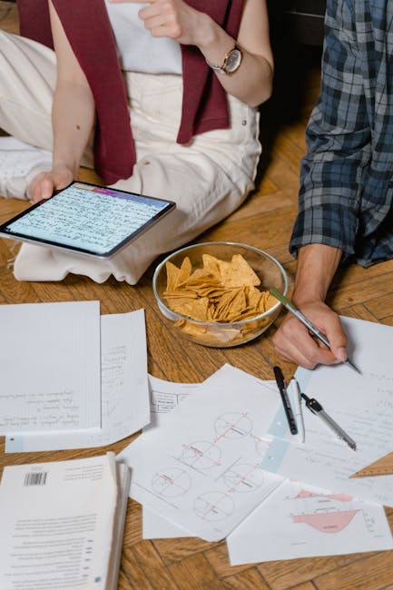 Studenti seduti a terra studiano con tablet e snack, metafora delle restrizioni alimentari per evitare i bagni scolastici.