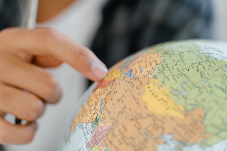 Mano che indica un punto sul mappamondo, simbolo di esplorazione e scoperta di risorse educative globali per la conoscenza.