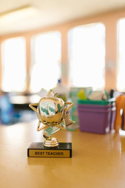 Trofeo dorato a forma di mela con la scritta Best Teacher, simbolo di eccellenza e riconoscimento nel contesto scolastico italiano.