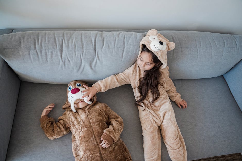 Bambini in pigiama a forma di orso e tricheco che giocano sul divano, stimolando la fantasia e il divertimento con travestimenti creativi