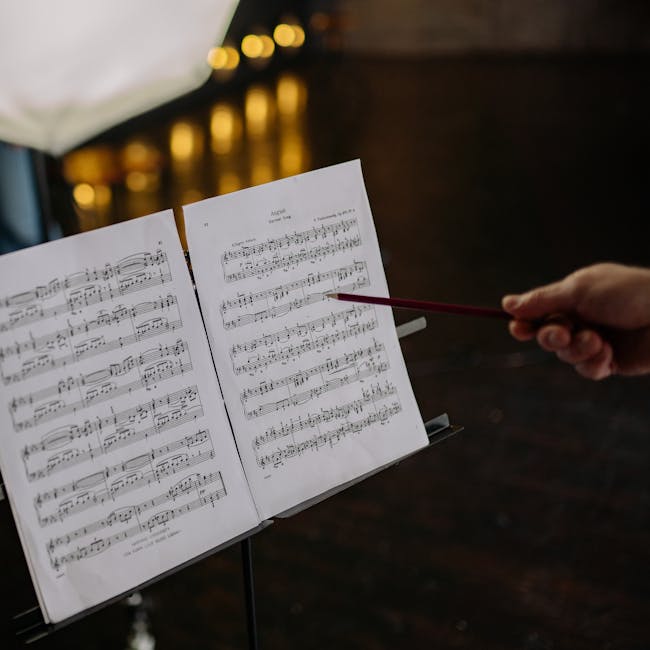Spartizione musicale e mano con matita rossa che indica una nota, metafora della valutazione e punteggio docenti precari