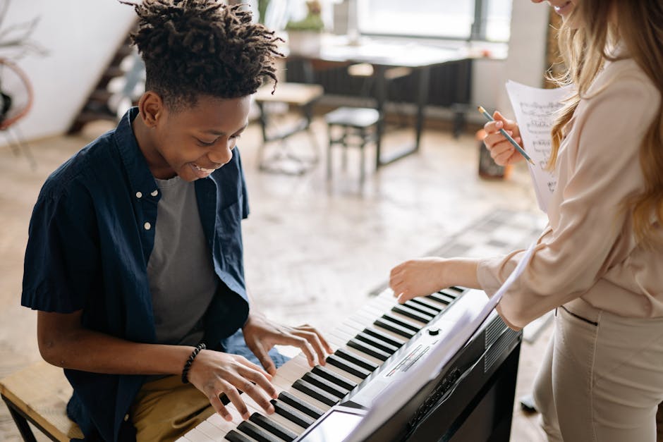 Ragazzo sorridente suona il pianoforte con insegnante, dimostrando l'importanza della musica nello sviluppo infantile e nell'apprendimento musicale.