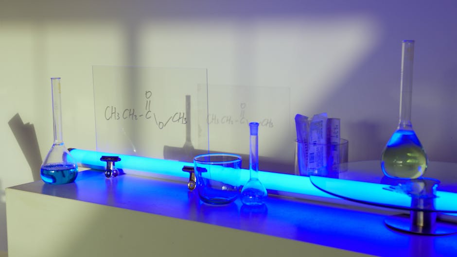 Vetreria da laboratorio illuminata di blu con formule chimiche, utile per illustrare concetti di geometria solida e calcolo dell'area del cilindro.