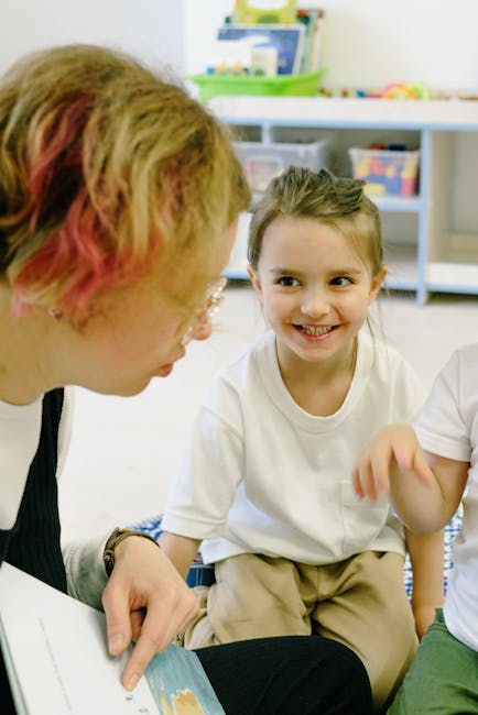 Iscrizione scuola infanzia 2026/27: maestra legge una storia a una bambina sorridente, ambiente scolastico accogliente e inclusivo.