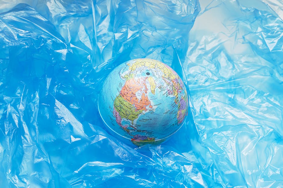 Globo terrestre avvolto in plastica blu, simbolo dell'inquinamento globale e dell'impatto sulla salute, ruolo dell'OMS nella tutela ambientale.