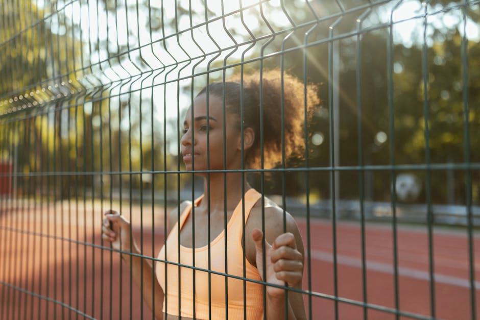 Atleta concentrata dietro una recinzione, visualizzazione e allenamento mentale per migliorare le performance sportive e raggiungere obiettivi.
