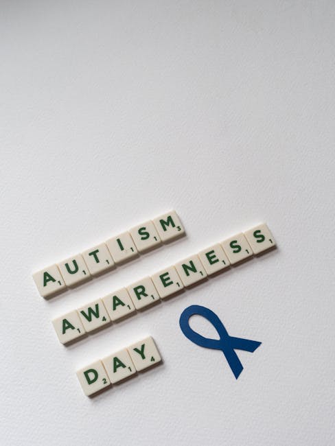 Giornata Mondiale Autismo: tessere Scrabble con scritta Autism Awareness Day e nastro blu simbolo della consapevolezza sull'autismo.