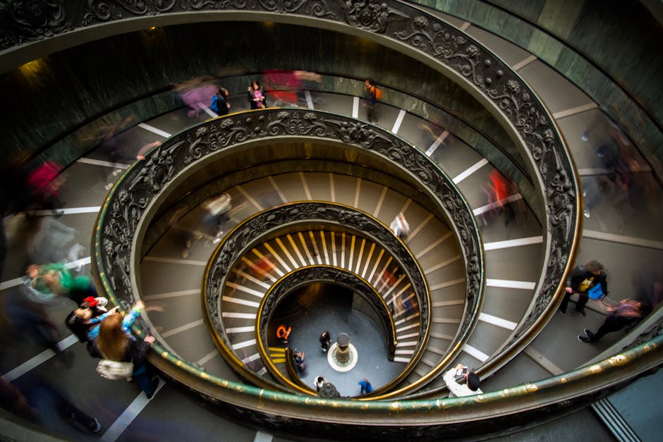Scala elicoidale Musei Vaticani con persone in movimento, simbolo di dinamiche complesse e interconnessioni globali nei contesti internazionali.
