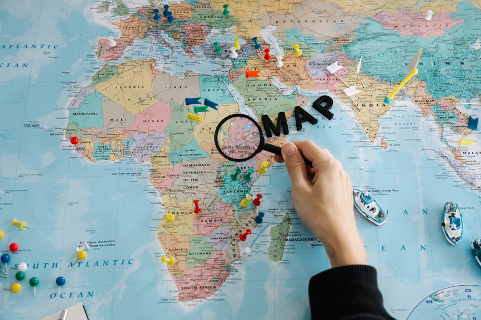 Mappa del mondo con puntine colorate e lente d'ingrandimento sull'Africa, ideale per illustrare la genetica umana e le sue origini geografiche.