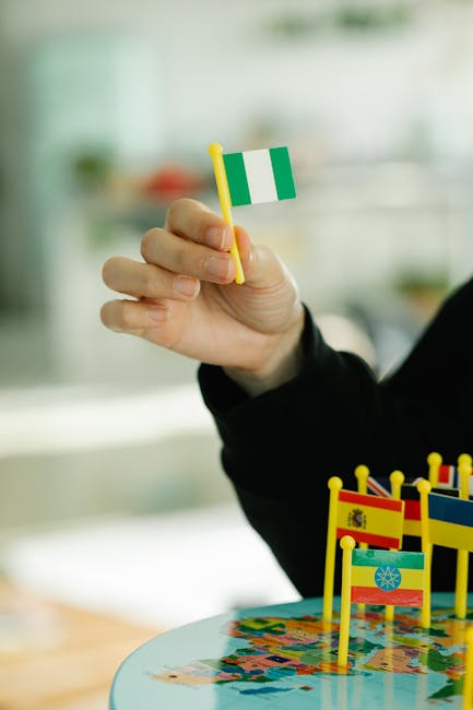 Analisi contesti internazionali: mano con bandiera Nigeria su mappa del mondo, simbolo di complessità globale e relazioni internazionali