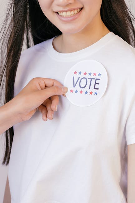 Giovane donna con spilla VOTE: importanza del voto e partecipazione civile secondo Cacciari in aula politica.