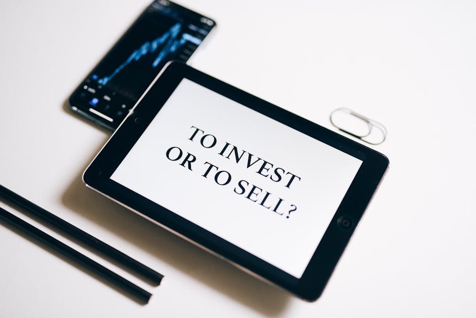 Tablet con scritta 'Investire o vendere?' e grafico finanziario su smartphone, riflessioni sulla retribuzione DSGA