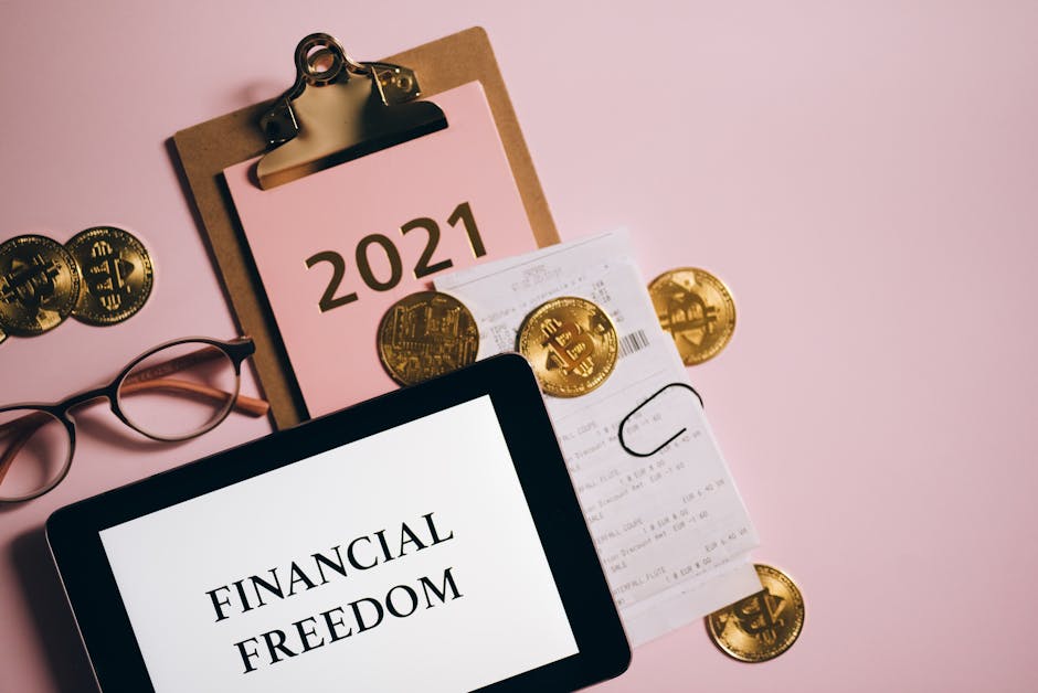 Pianificazione finanziaria personale: tablet con scritta Financial Freedom, monete Bitcoin, scontrino e agenda 2021 per il futuro finanziario.