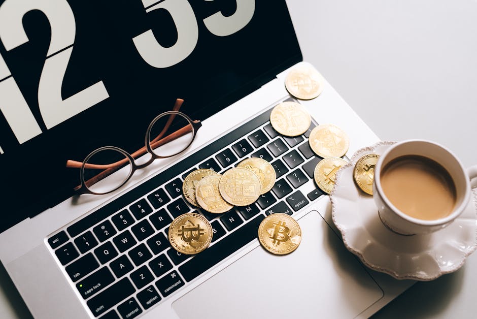 Bitcoin su laptop con tazza di caffè e occhiali, simbolo di Fintech e Blockchain per l'innovazione finanziaria digitale.