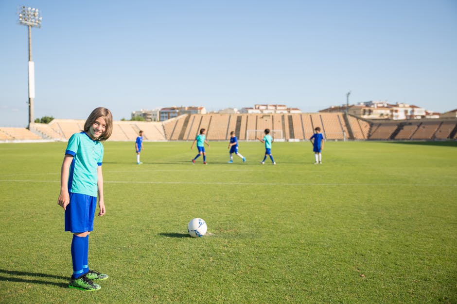 Bambino sorridente in campo da calcio con compagni, esempio di apprendimento attivo e sviluppo del potenziale attraverso lo sport.
