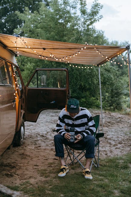 Fotografo con macchina fotografica vintage vicino al camper illuminato, celebrazione della Giornata Mondiale delle Telecomunicazioni.
