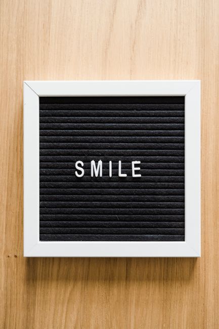 Lettera con la parola SMILE su sfondo di legno, simbolo di positività e gioia