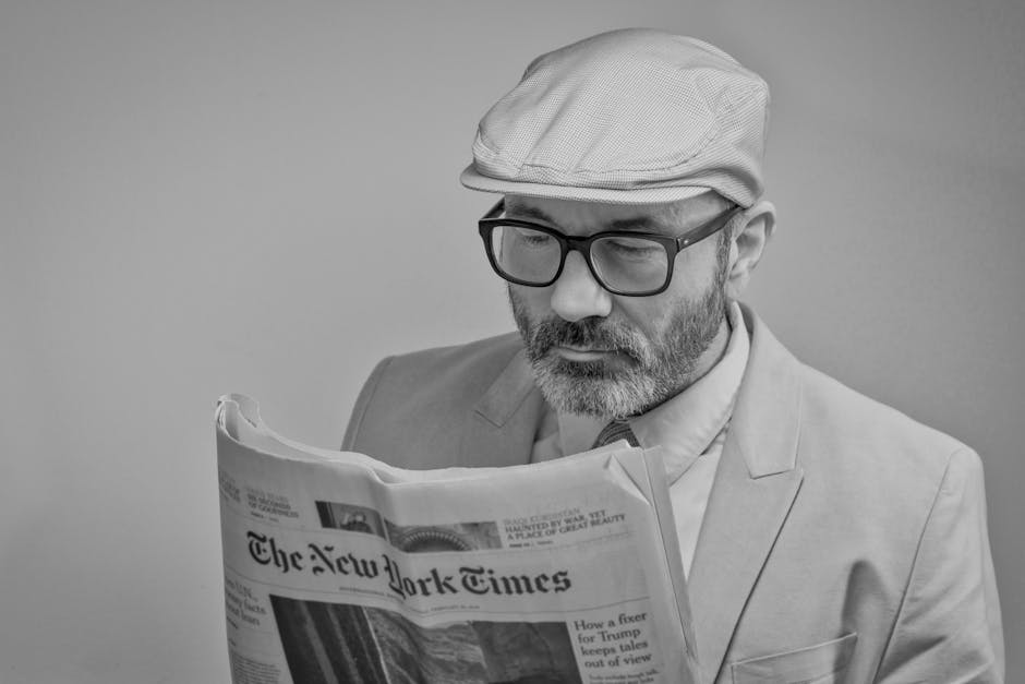 Uomo legge il New York Times in bianco e nero, riflettendo sulla serietà della nuova maturità secondo Valditara. Focus sull'istruzione e l'informazione.