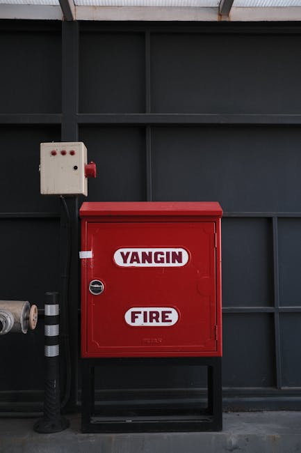 Cassetta antincendio rossa con scritta 'YANGIN FIRE', simbolo di sicurezza e prevenzione in contesti scolastici e gestione della devianza.