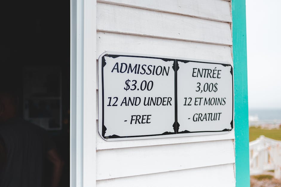 Cartello bilingue con tariffe d'ingresso: 3 dollari, gratuito sotto i 12 anni. Rilevanza per requisiti di ammissione GPS 2026/2028.